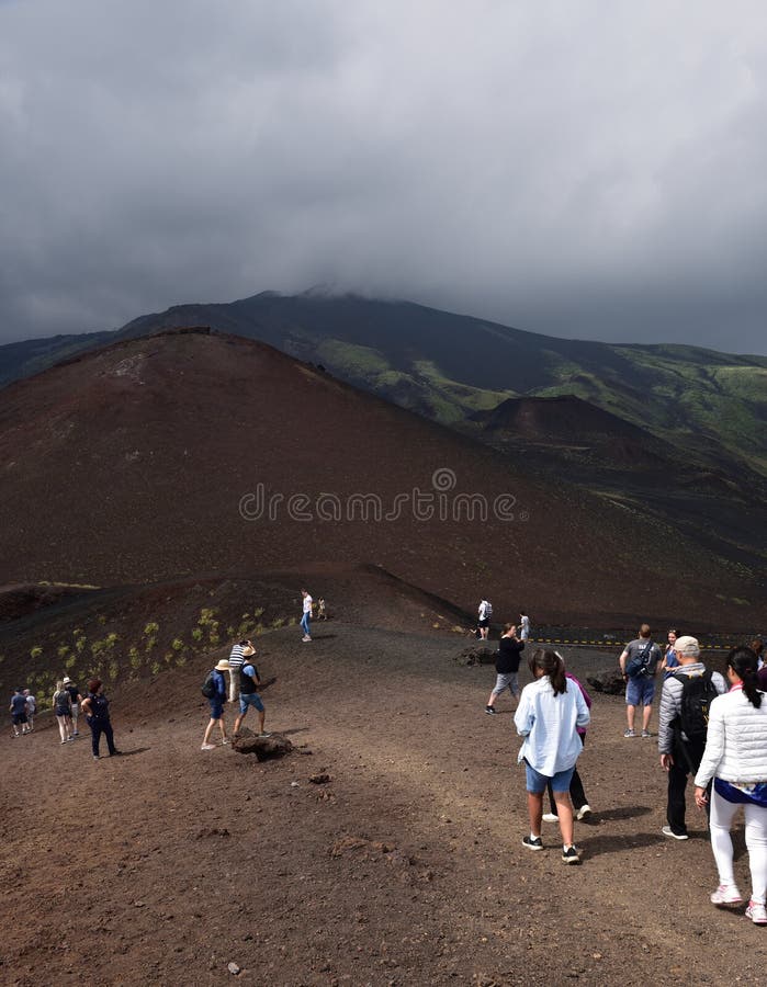Туристы и темные облака над горой Этна
